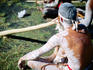 Indigenous performer playing didgeridoo at market.