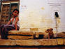 Boy sitting on a sidewalk with a puppy dog.