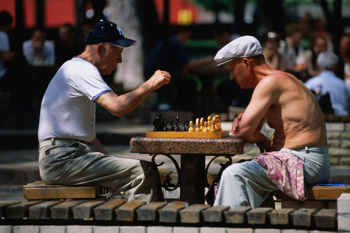 Men playing chess under chestnut trees in Shevchhenko Park.
