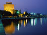 White Tower, 15th century symbol of Thessaloniki, reflected on water at night.
