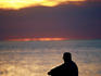Man sitting at sunset at Glenelg pier.