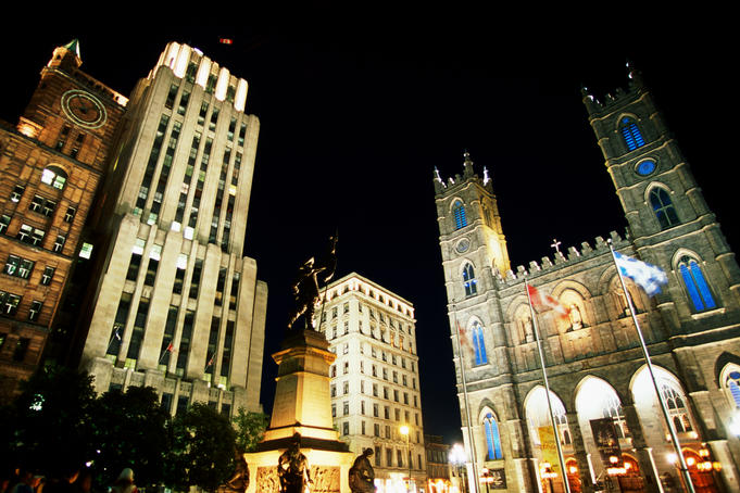 Place d'Armes and Notre-Dame Basilica illuminated at night.