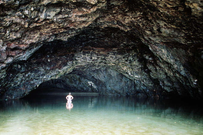 Hiker explores cave at Kalalau Beach.