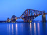 Oblique view of the Firth of Forth, Forth railway bridge floodlit at dusk. The bridge completed in 1890 replaced the Tay bridge which collapsed in high winds. The Forth bridge was overly constructed to regain public confidence. It was the longest span in the world until 1917, and is still the second longest today and is the bridge that ushered in the era of the great cantilever style.