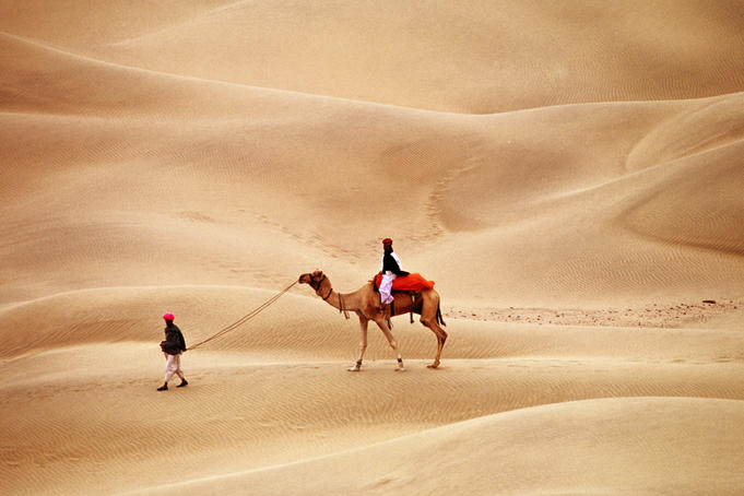 Overhead of Rajasthani men with camel on dunes.