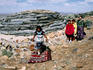 Navajo girl dancing with family and hogan (house) behind.