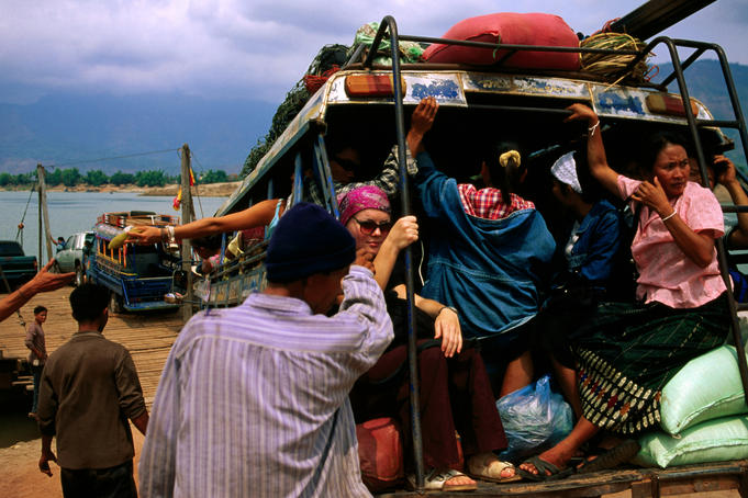 Bus loaded with people driving onto ferry to cross Mekong river.