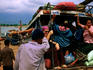 Bus loaded with people driving onto ferry to cross Mekong river.