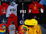 Various tops and t-shirts with USA National Security logos displayed for sale.