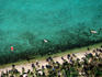 Aerial of palm-lined beach and boats in lagoon.