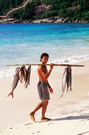 Fisherman with catch on beach.