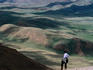 Trekker looking out at hills and meadows outside of Kochkor, Kyrgyzstan