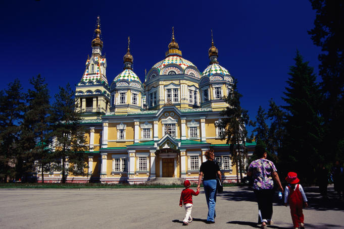 Family walking outside Zenkov Cathedral in Panfilov Park.