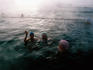 People swimming in outdoor heated pool in winter.