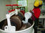 Worker adding sugar to cocoa being grounded in melangeur machine, Grenada Chocolate Company, Hermitage.