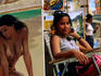Woman on chair next to erotic painting at Calle Tacon artisans market.