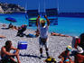 Man on beach holding up chairs for rent.