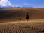 People horse riding in sand dunes.