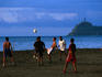 Boys playing soccer game on beach.