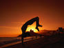 Man doing somersault on beach at sunset.