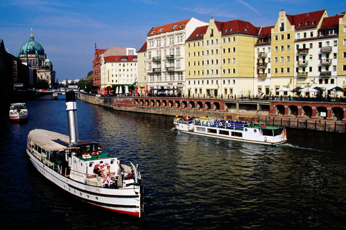 Tourist boats on Spree River with Berlin Cathedral in background.