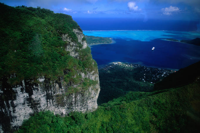 Aerial view of mountains and bay near Tipoto, with Renaissance cruise ship in distance.