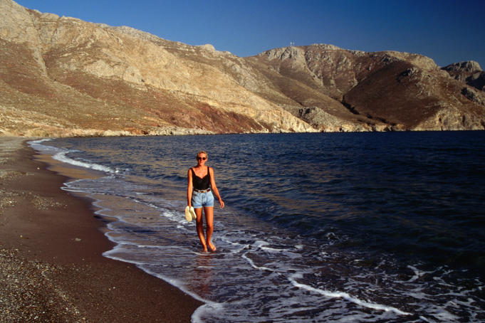 Woman walking along tranquil beach, Tilos.