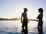 Children standing in water at sunset.