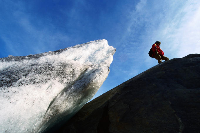Hiker on rock beside Aletschgletscher glacier.