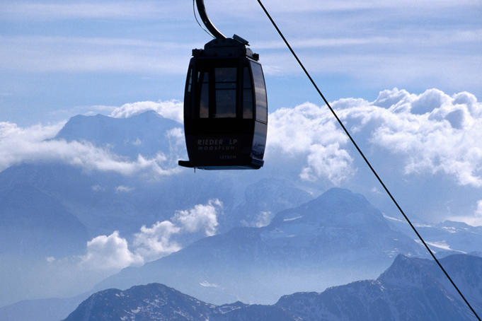 Moosfluh ropeway with peaks and clouds in background.