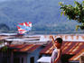 village boy flying kite over iron rooftops.
