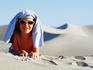 Boy in sunglasses lying in dunes.