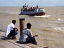 Boys on pier watching ferry on Correntyne River to Suriname.