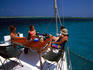 Tourists sitting around table on deck of sailing vessel.