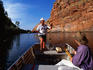 Two people fishing in a gorge from a dinghy.