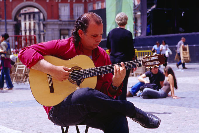 Busker playing guitar on Plaza Mayo, Sol.