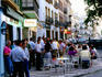 People standing outside bar, early evening.