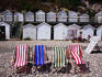 Striped deckchairs and bathing huts on pebbled Beer beach.