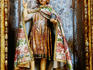 Painted and gilded saint statue in niche of village church.