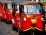 Three-wheeled Bajaj transportation lined up in street.