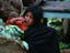 A girl in the market leaning on a sack of cabbages
