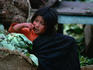 A girl in the market leaning on a sack of cabbages