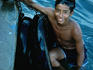 A boy swimming in the water at the Acapulco pier, wearing a mask on his head