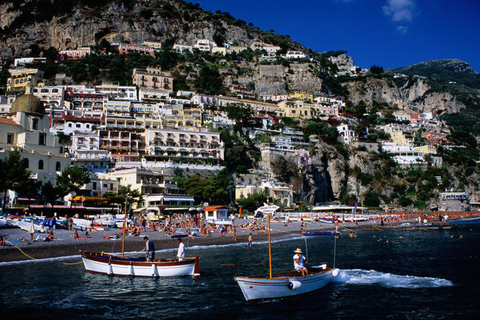 Houses terraced into rugged Amalfi coastline, boats in foreground.