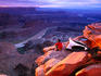 Man camping on edge of rocky cliff.