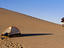 Hiker with backpack walks away from tent at Imperial Sand Dunes.