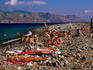 Sunbathers on stone beach with Lipari in background.