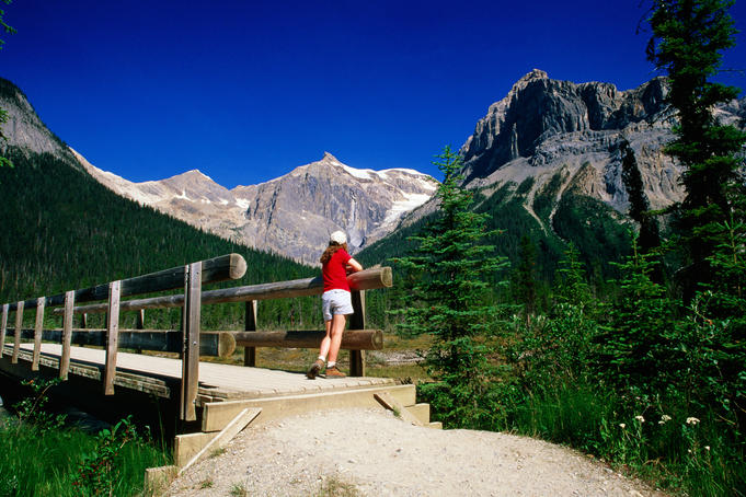 Hiker on bridge near Emerald Lake with mountain backdrop.