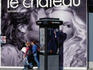People walking past a billboard on Rue St Denis.