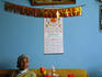Woman sitting under framed picture of Machu Picchu and calendar in the living room of a Peruvian house.